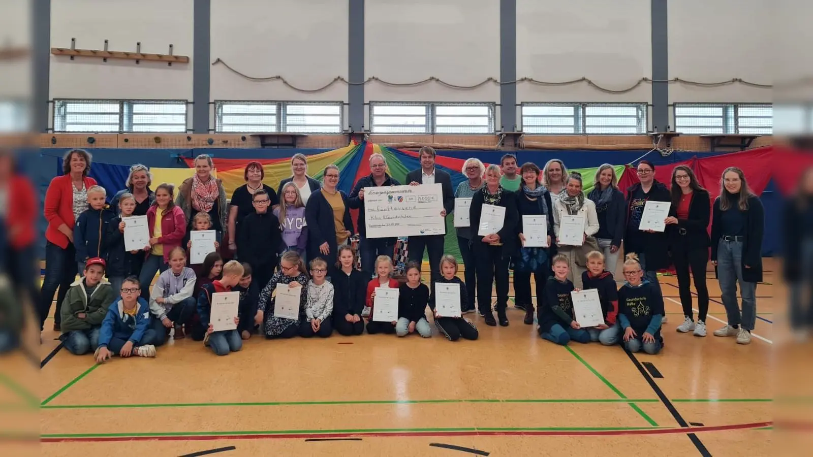 Prämienübergabe in Bodenwerder: Samtgemeindebürgermeister Sebastian Rode (in der Mitte rechts) und sein Allgemeiner Vertreter Fred Burkert (links) mit dem symbolischen Scheck über 5000 € - umringt von Kindern und Vertreter:innen der klimaengagierten Kitas und Grundschulen der Samtgemeinde, für die das Geld bestimmt ist.  (Foto: privat)