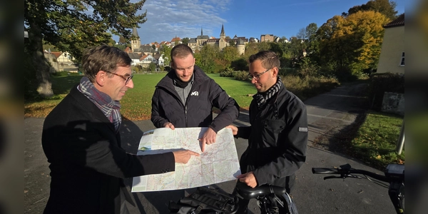 Hier liegt die Hansestadt Warburg: Bürgermeister Tobias Scherf (von links), Touristiker Lucas Lambracht und der Mobilitätsbeauftragte Jan Kolditz betrachten die neuen Tourenkarte für Radfahrer.  (Foto: Hansestadt Warburg)