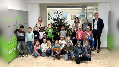 Die Kinder der 1A mit ihrer Lehrerin Frau Rüther-Lommel sowie Carmen Watermeyer-Fels, Irma Sabotic und Michael Starp (v.l.) von der BeSte vor dem bunt geschmückten Weihnachtsbaum. (Foto: BeSte Stadtwerke GmbH)